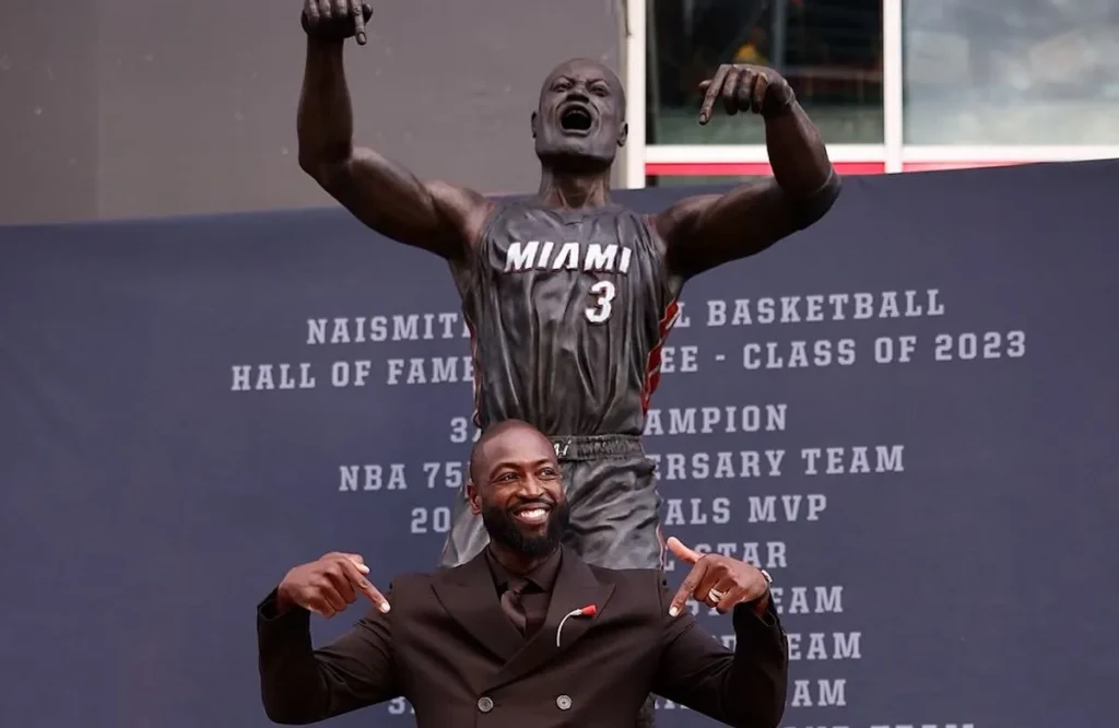 Dwyane Wade's statue being unveiled at Kaseya Center in Miami with fans and media present.